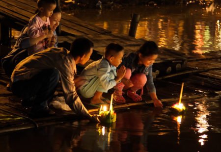 On the night of the twelfth lunar month, when the full moon is shining brightly and the monsoon season has ended, all bodies of water, rivers and klongs (canals) in Thailand are ablaze with light. In Thai, “loy” means float and “krathong” are the small handmade raft –or banana leaf boats– decorated with candles, incense and flowers. Inspired by the Hindu tradition, Diwali, Loy Krathong was first celebrated in Sukhothai. While it pays homage to the Goddess of Water and thanks her for her precious help at harvest, other beliefs revolve around this celebration. It symbolises renewal and is considered a moment of purification where grudges and anger float away with the krathong. Some people even leave locks of hair or nail clippings, which symbolise their defects.